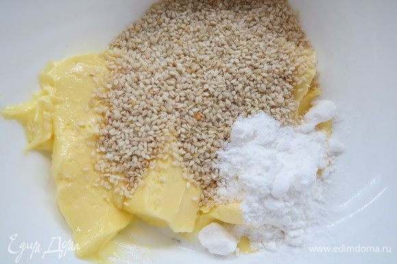 В миске смешать слегка растопленное масло с разрыхлителем и 4 ст. л. сахарной пудры, затем добавить кунжут. Вымесить до однородности.