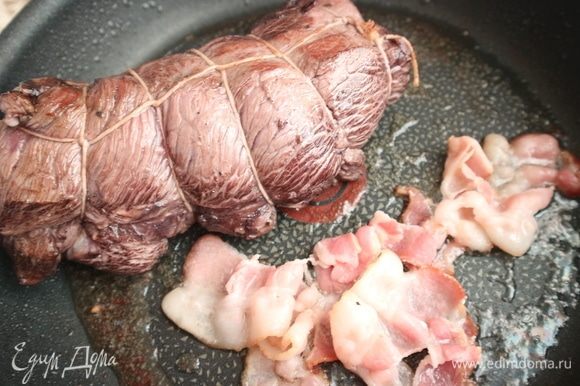 Поджарить мясо со всех сторон на раскаленной сковороде с добавлением оливкового масла и бекона. Разогреть духовку до температуры 180°С.