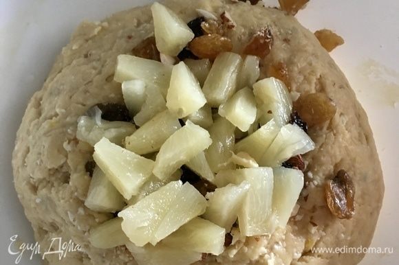 В тесто добавить орехи, изюм и ананасы. Тщательно вмешать их в тесто.