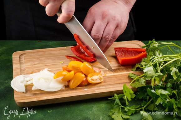 Нарежьте лук полукольцами, а болгарский перец — полосками, помидоры черри — пополам. Измельчите петрушку.