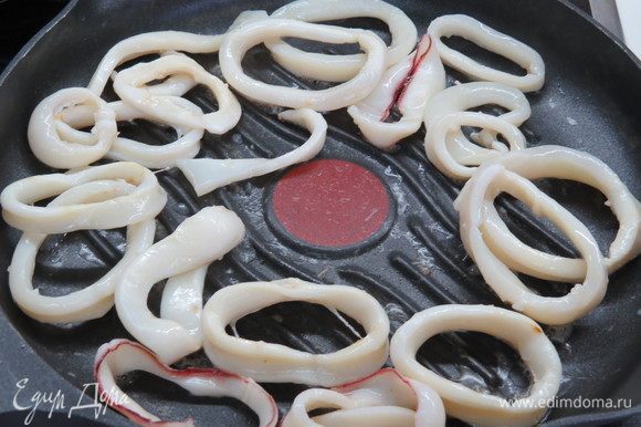 Сковороду-гриль (можно взять и обычную) смазать тонким слоем растительного масла, обжарить кольца кальмаров на сильном огне 2–3 минуты. Затем убираем кальмаров со сковороды, откладываем в сторону.