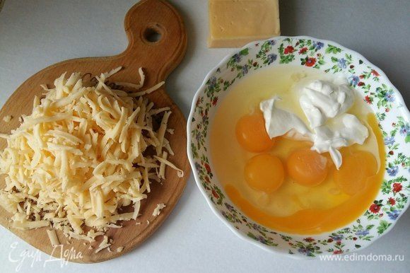 Подготовим заливку. Разбить 4 яйца, добавить к ним 2 ст. л. сметаны, перемешать. Добавить натертый сыр.