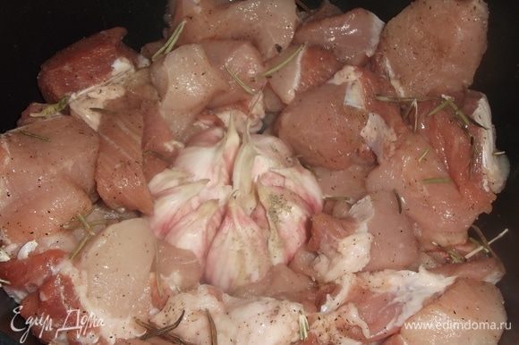 Свинину нарезать на крупные куски, посолить, поперчить. Выложить в посуду. С головки чеснока снять верхнюю шелуху, при этом оставляя головку целиком. Выложить в середину мяса, добавить розмарин.