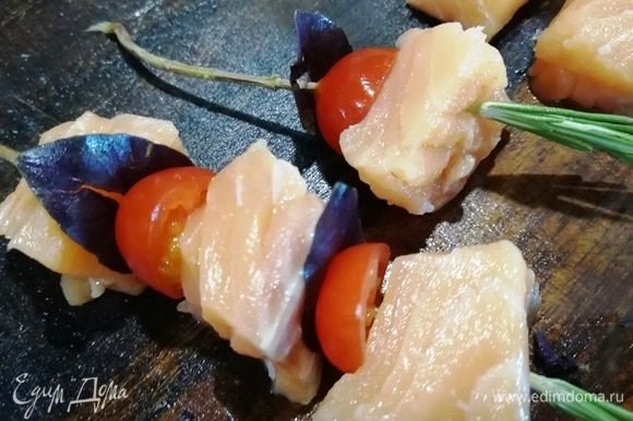 На веточку розмарина нанизываем кусочек лосося, половинку помидора черри, листик базилика. Чередуем.