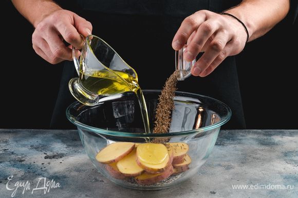 В емкости соедините оливковое масло, соль, перец, тмин. Замаринуйте картофель на 15 минут.