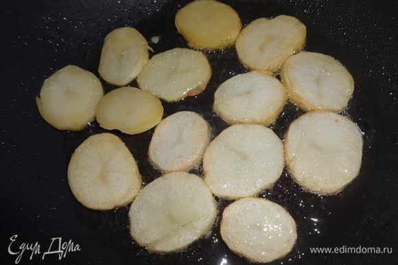 В сковороде разогреть растительное масло и обжарить на нем кружки картофеля с двух сторон до румяной корочки.