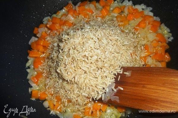 Рис предварительно промыть под проточной водой, дать воде стечь. Положить рис в сковороду с обжаренными морковью и луком, перемешать. Продолжать обжаривать все вместе еще 5 мин.