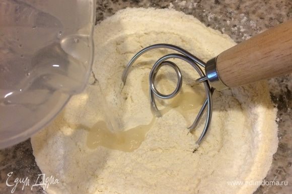 Просеять в миску все три вида муки, добавить соль и перемешать. Сделать в муке лунку, добавить слегка теплую воду.