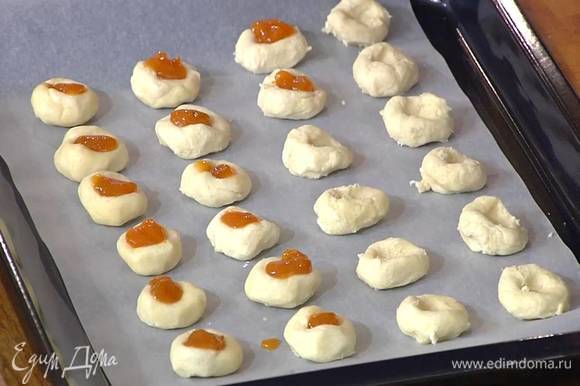 В углубления выложить понемногу абрикосового джема и выпекать печенье в разогретой духовке 12–15 минут.