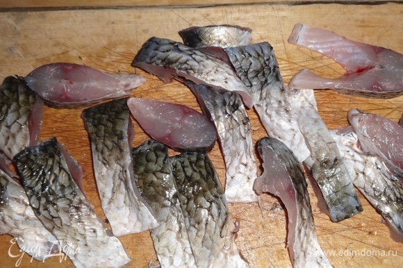 Нарезать тушки рыбы на мелкие кусочки, одновременно удаляя плавники.