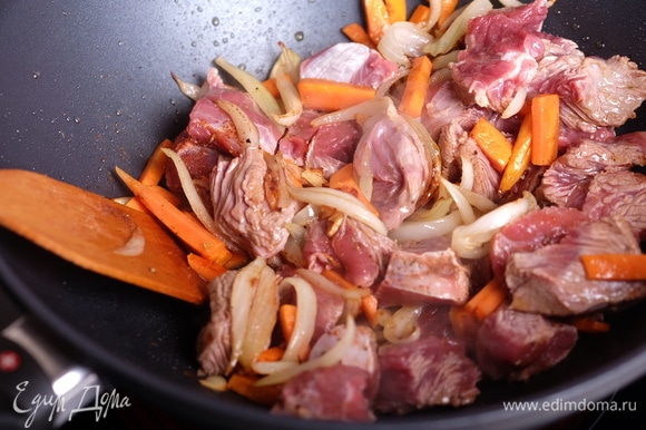 Следом добавить морковь, жарить еще 5 минут. Добавить мясо и специи, жарить 5 минут, пока мясо не станет матовым.