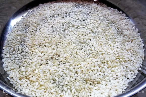 В глубокую сковороду наливаем 3 ст. л. оливкового масла, высыпаем рис и обжариваем его на среднем огне, помешивая, 2 минуты. По краям рис станет прозрачным, а в середине — белым.