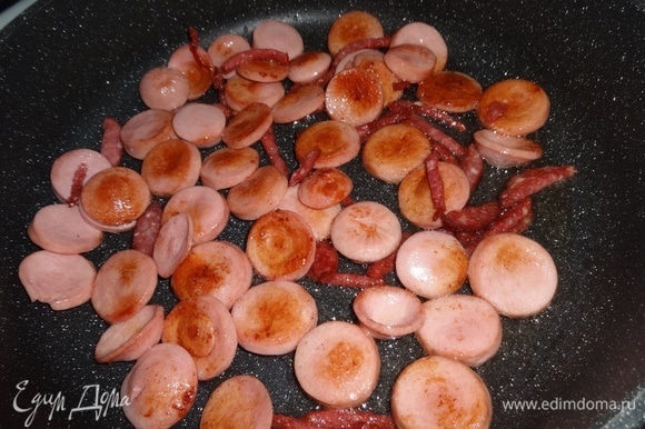 Нарезанные сосиски и колбасу выложить в разогретый жир от бекона и обжарить до румяности. Обжаренные продукты выложить в миску с беконом, оставляя жир в сковороде.