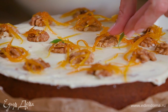 Остывший пирог смазать сливочным кремом, украсить половинками грецких орехов, апельсиновой карамелью и листьями базилика.
