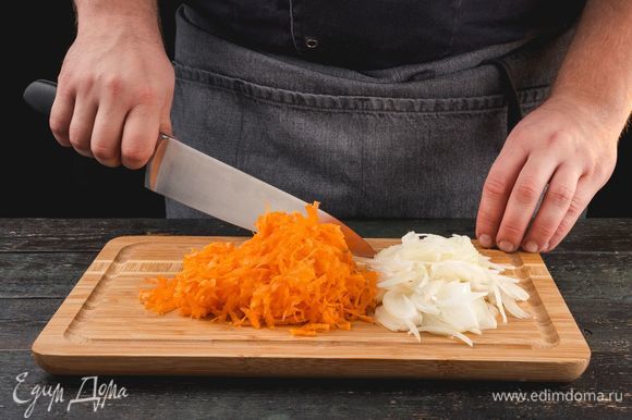 Очистите луковицу и нарежьте ее средними кубиками. Морковь натрите на крупной терке. Обжарьте овощи на сковороде с растительным маслом, постоянно помешивая.