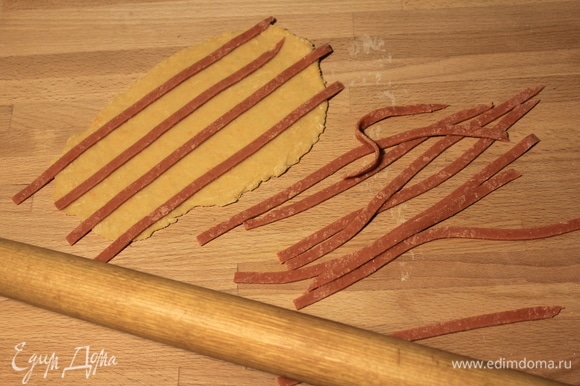 Красный пласт разрезаем на полоски шириной около 4–5 мм и накладываем их на оранжевое тесто.