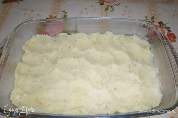 В смазанную форму выкладываем половину картофельного пюре. Равномерно распределяем.