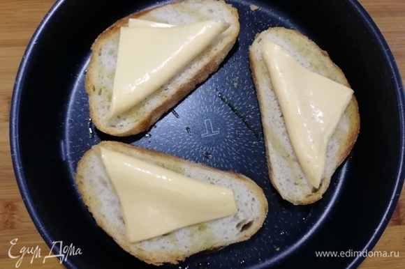 На горячий хлеб кладем по пластинке плавленого сыра.