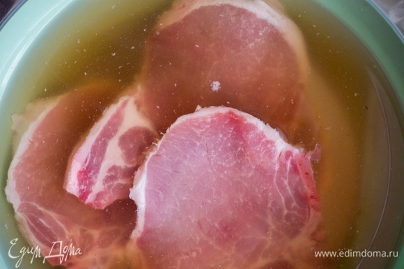 Сначала замаринуйте свиные отбивные. Налейте в миску воду, добавьте сахар, соль и перемешайте. Поместите в миску свиные отбивные и оставьте на 1 час.