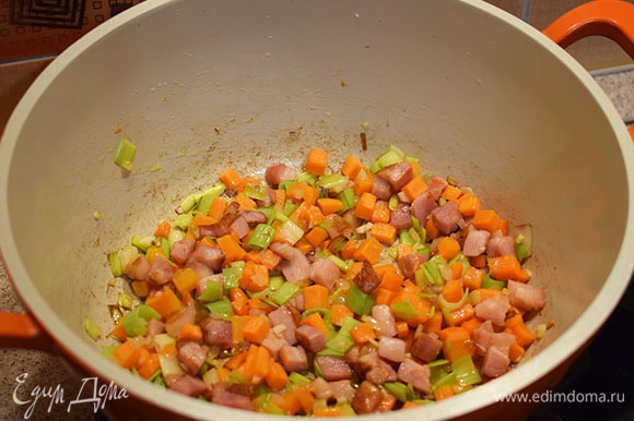 Добавить в кастрюлю морковь, лук-порей, лук репчатый и чеснок. Обжарить до золотистого цвета.