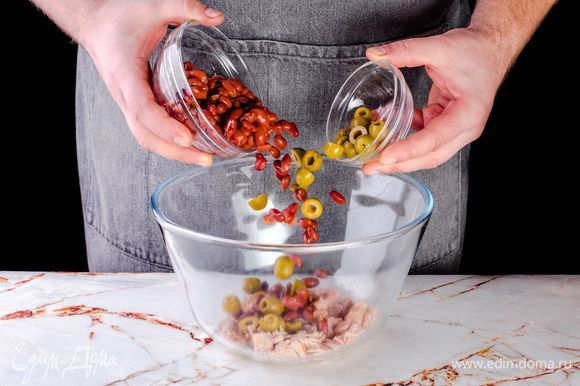 В салатник к тунцу отправьте нарезанные оливки и фасоль.
