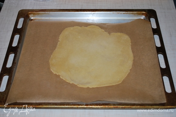 Раскатайте тесто на пергаменте и наколите его вилкой, чтобы оно не пузырилось. Выпекайте в духовке до золотистого цвета примерно 3–4 минуты при температуре 180°C.