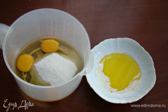 Сливочное масло растопить и остудить до комнатной температуры. Яйца взбить с сахаром в пышную светлую массу. Затем к этой массе влить остывшее сливочное масло и все перемешать до однородности.
