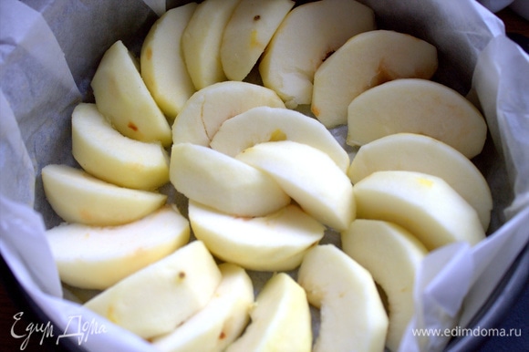 Застелить форму пергаментом, смазанным сливочным маслом, и выложить на дно дольки яблок.