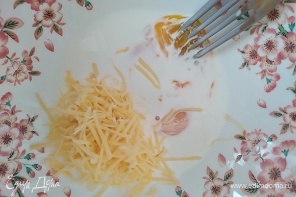Сыр натереть на мелкой терке. Смешать в миске желток, сливки и половину тертого сыра. Добавить лимонный сок и цедру.