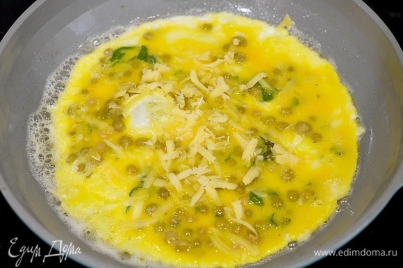 Когда омлет слегка схватится, посыпьте его тертым сыром.
