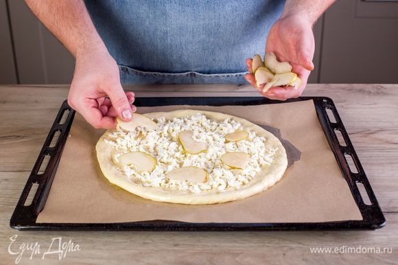 Выложите на тесто тертый сыр моцарелла, ломтики груши.