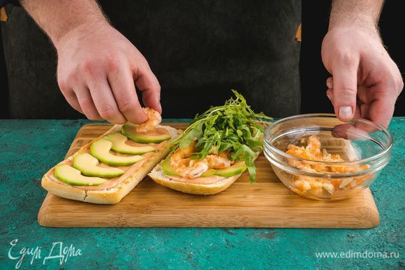 Соберите брускетту: на подсушенную чиабатту выложите соус, авокадо, креветки и руколу.