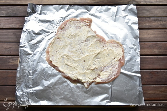 Творожный сыр смешать с солью, чесноком и приправой для курицы. Отбитое филе переложить на кусок фольги. Смазать смесью творожного сыра со специями.