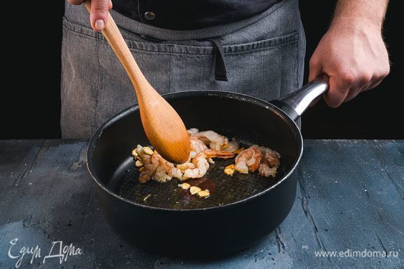 В сковороду добавьте растительное масло и мелко нарезанный чеснок. Обжарьте чеснок до золотистого цвета. Добавьте в сковороду креветки и обжаривайте их до готовности 2–3 минуты.