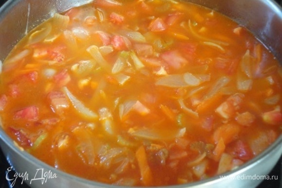 Выложить к овощам томатную пасту и помидоры и влить бульон. Тушить 10–15 минут при открытой крышке.