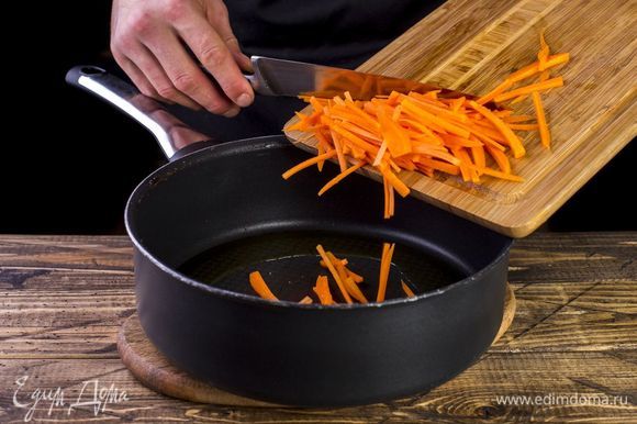 Морковь нарежьте соломкой. Налейте в сотейник масло и выложите морковь. Немного обжарьте.