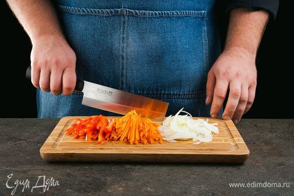 Изюм промойте и залейте кипятком. Оставьте его на 30 минут. Лук, морковь и перец нарежьте соломкой.