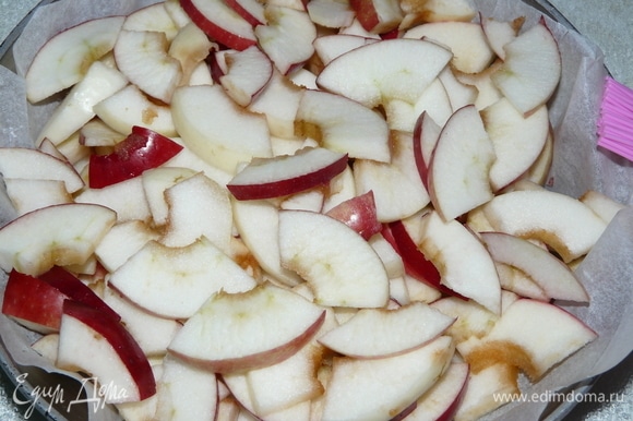 Нарезаем яблоки сначала дольками, а потом — кусочками. Заранее приготовим форму: смазываем растительным маслом и дно посыпаем панировочными сухарями. Я положила пергамент между формой и пирогом. Далее выкладываем нарезанные яблоки. И отодвигаем в сторону.
