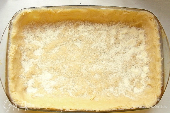 Достаньте тесто из холодильника и распределите ровным слоем по дну и бортикам формы. Посыпьте дно манной крупой.