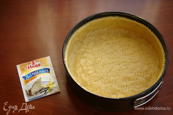 Дно формы для выпечки (20–22 см) застелить пекарской бумагой и равномерным слоем выложить песочное тесто, делая высокие бортики. Дно наколоть вилкой и поставить в холодильник минут на 30.