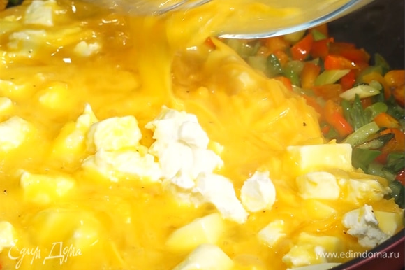 Овощи на сковороде залить яично-сырной массой, перемешать, посыпать оставшимся чеддером.