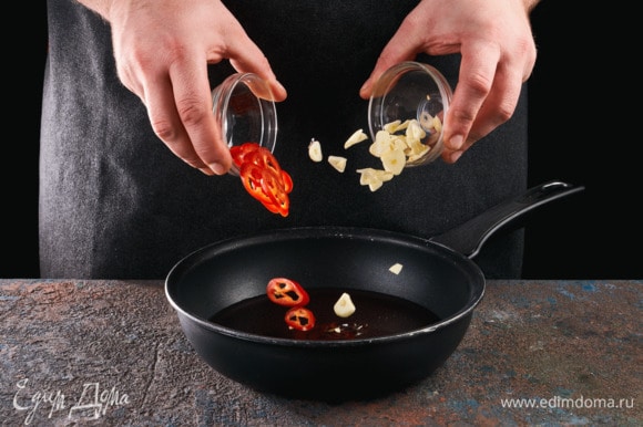 Чеснок и перец чили нарежьте кружочками. В сковороде слегка нагрейте оливковое масло, обжарьте в нем чили и чеснок до золотистого цвета.