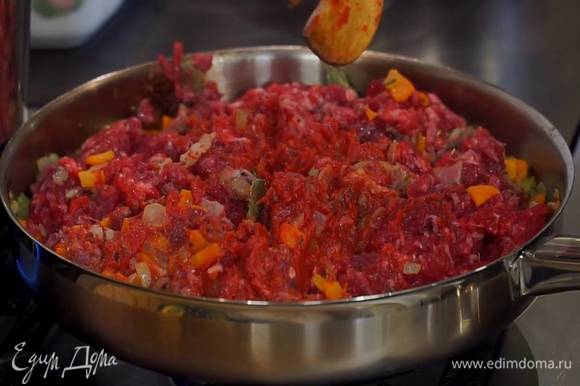 Фарш небольшими порциями выкладывать к овощам с панчеттой, каждый раз вымешивая лопаткой, затем добавить томатную пасту и все перемешать.