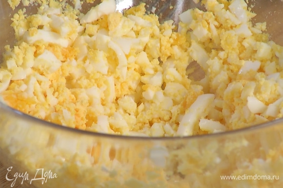 Предварительно отварить яйца вкрутую, очистить, размять их вилкой в миске.