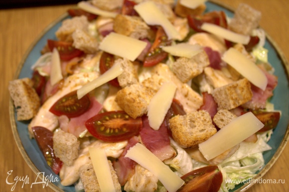Перенести дольки на блюдо и с помощью овощечистки посыпать слайсами твердого сыра.