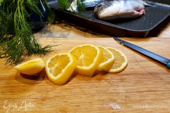 Теперь самый нужный ингредиент — лимон. Нарезаем и закладываем в рыбу.