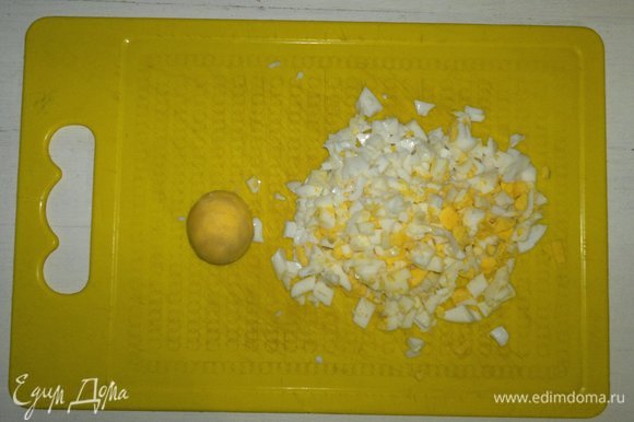 Вареные яйца почистить. Один желток отложить для украшения, остальные яйца мелко нарезать.
