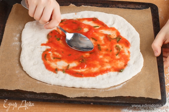 Поместить раскатанное тесто на противень, предварительно застеленный бумагой для выпечки. Выложить часть соуса и распределить его по тесту.