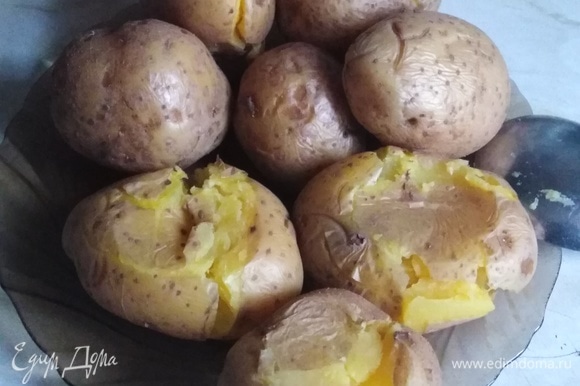 Отварной в мундире картофель примять ложкой, стараясь не допустить разлома картошки.