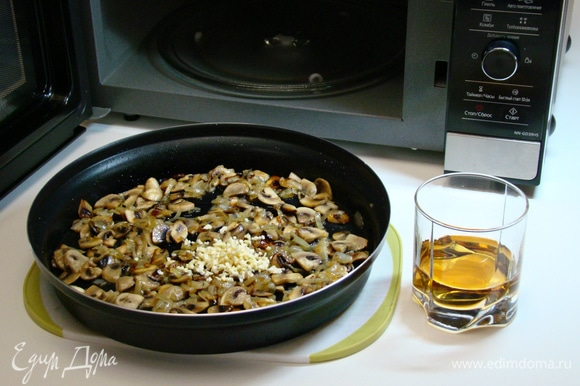 К обжаренным луку и грибам добавить измельченный чеснок и влить белое сухое вино. Перемешать и выпарить при средней мощности (600 Вт) в течение 5 минут.